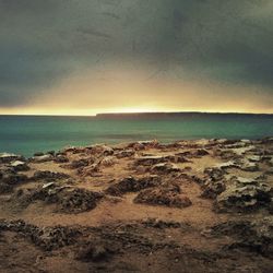 Scenic view of beach against sky at sunset