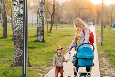 Mom walks with stroller and toddler son in the park