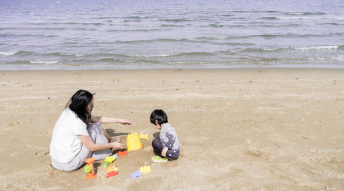 Rear view of women sitting on beach