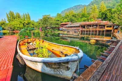 Boats moored by lake against sky