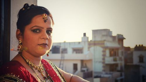 Portrait of woman standing on balcony against buildings