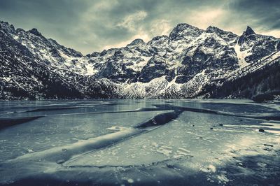 Frozen lake against snow covered rocky mountains