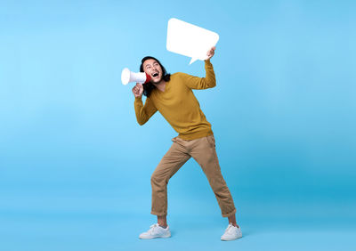 Full length of happy man standing against blue background