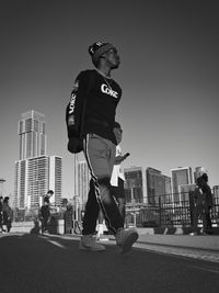 Man skateboarding on city street against clear sky