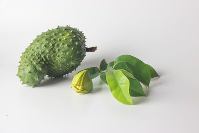 Close-up of green fruit on table against white background