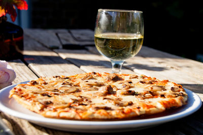 Close-up of drink by pizza on wooden table