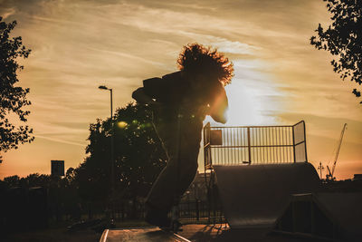 Silhouette man skateboarding in park against sky during sunset