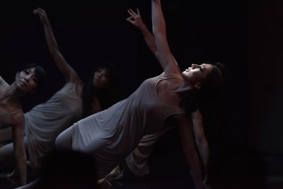 Women dancing against black background