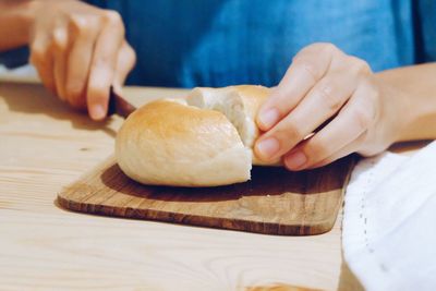 Midsection of woman cutting bread on table