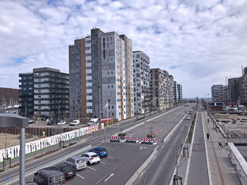 Vehicles on road by buildings against sky