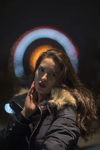 Close-up portrait of beautiful young woman wearing warm clothing at night