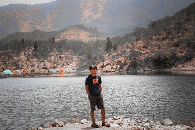 Man standing by lake against mountains