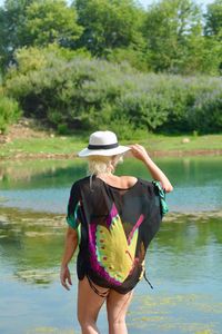 Rear view of woman standing by lake