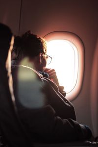 Close-up of man looking out airplane window
