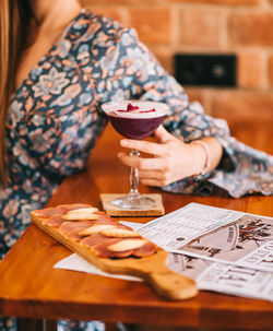 Midsection of woman holding ice cream on table