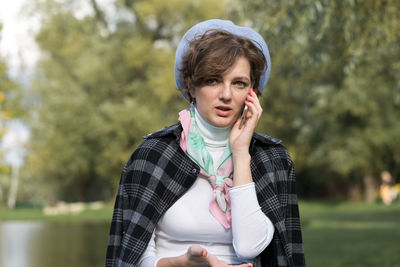 Portrait of young woman looking away while standing outdoors