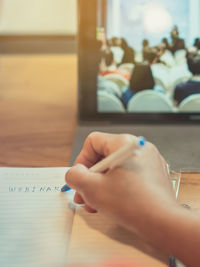 Cropped hand of woman writing on diary