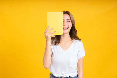 Portrait of a smiling young woman against yellow background