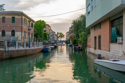 Canal amidst buildings in city against sky during sunset