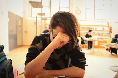 Young man with head in hands sitting at restaurant