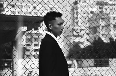 Portrait of boy standing by chainlink fence