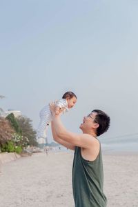 Happy mid adult man holding toddler boy at beach