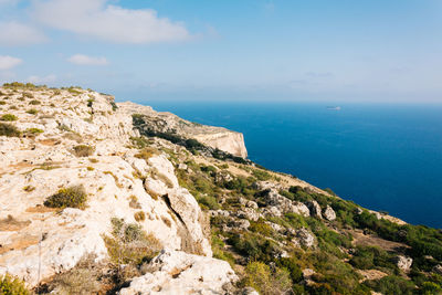 Scenic view of rocky mountain by sea against sky