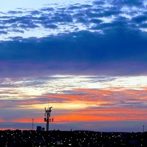 Silhouette buildings against dramatic sky during sunset