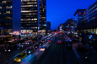 Illuminated vehicles on street in city against sky at night