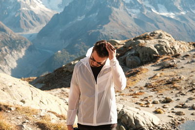 Young man wearing sunglasses while standing against mountain