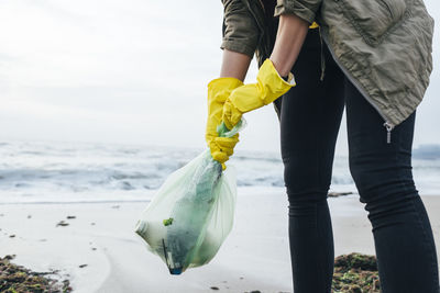 Woman collecting plastic waste at beach