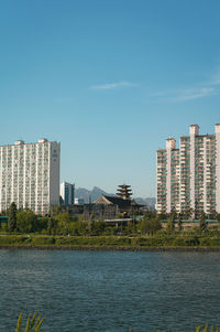 Sea by buildings against sky in city