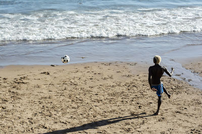 Young model playing sand football on the beach under strong summer sun. salvador bahia brazil.