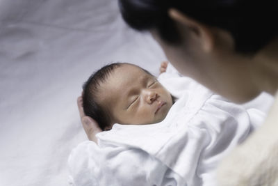 Close-up of mother holding newborn son on bed