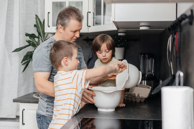 Father teaching kids cooking in kitchen