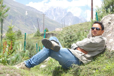 Man relaxing on sunglasses against mountain range