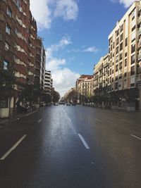 Road amidst buildings in city against sky