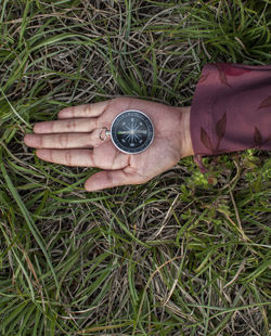 Close-up of woman holding navigational compass on field