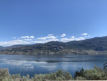 Scenic view of lake and mountains against blue sky