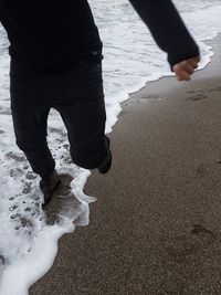 Low section of people walking on beach