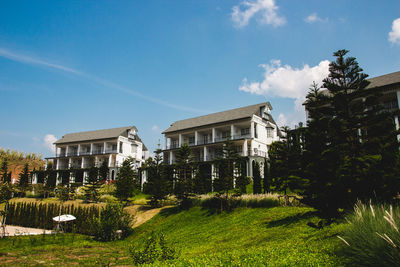 Building and trees on field against blue sky