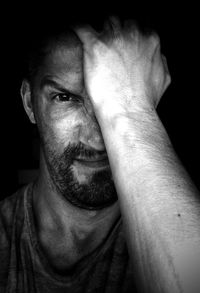 Close-up portrait of frustrated man against black background