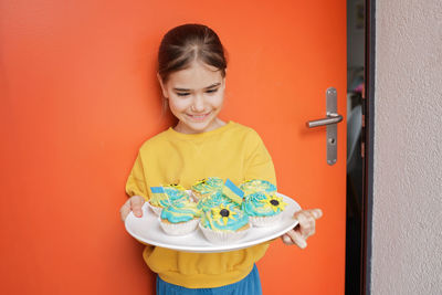 Ukrainian girl for whom neighbors brought cupcakes with cream in yellow and blue colors for brunch