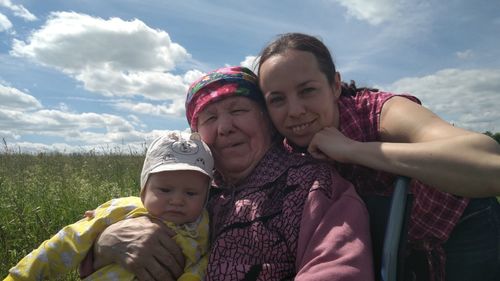 Portrait of mother and daughter on field against sky