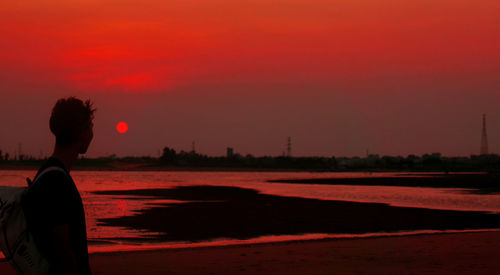 Side view of silhouette woman standing on land against sky during sunset