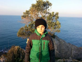 Portrait of boy standing against sea and sky