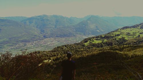 Rear view of woman standing on mountain against sky