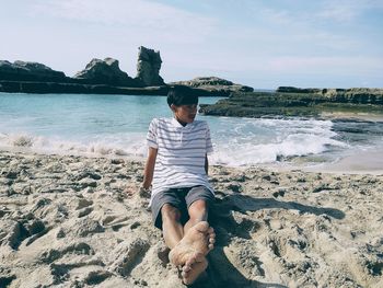 Midsection of man at beach against sky