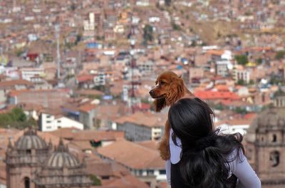 Rear view of woman with dog against cityscape