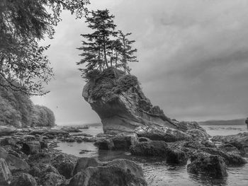 Rock formation by sea against sky